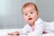 Close-up portrait of a happy baby lying on the bed. Copy space. The concept of parenthood and family planning