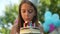 Close-up portrait of happy girl blowing out candles on birthday cake in slow motion smiling. Positive satisfied