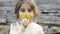 Close up portrait of a happy little girl in garden picking up and smelling some yellow flowers