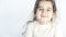 Close up portrait of a happy little girl looking directly to camera in front of white wall