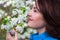 close up portrait of happy middle aged woman smelling cherry tree branch in garden