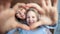 Close-up portrait of happy mother and daughter showing gesture love heart by hands