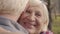 Close-up portrait of a happy senior Caucasian woman hugging her adorable husband. Mature retired couple spending sunny