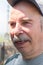 close-up portrait happy senior man in cap, not looking at camera, in nature, on sunny day