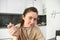 Close up portrait of happy smiling brunette in bathrobe, holding cereals in spoon, eating breakfast with milk and