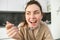 Close up portrait of happy smiling brunette in bathrobe, holding cereals in spoon, eating breakfast with milk and