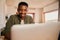 Close up portrait of a happy Young adult black African-American male smiling while using his laptop. Remote working from