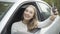 Close-up portrait of happy young beautiful Caucasian woman bragging car keys sitting on driver`s seat. Joyful smiling