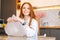 Close-up portrait of happy young woman playing pops bubble wrap to calm herself sitting at table in kitchen room.