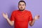 Close up portrait of helpless young handsome man raising hands, being disappoined, wearing red casual t shirt, standing isolated