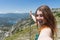 Close up portrait Hiker girl smiling and laughing holding a wood stick. Excursionist red head woman taking a selfie with smart