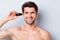 Close-up portrait of his he nice attractive bearded cheery brown-haired guy shaving picking cutting unwanted hair in ear