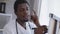 Close-up portrait of intelligent thoughtful African American young man writing on flipchart standing in hospital office