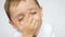 Close-up: portrait of a joyful child. The boy laughs and closes his mouth with his hand