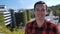 Close-up portrait of joyful young man in plaid shirt smiling laughing looking at camera outdoors on the roof at urban