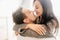 Close-up portrait of kissing couple spending morning together. Indoor photo of blissful european girl with long black