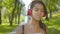 Close-up portrait of little African American girl in headphones walking in summer park and listening to music. Absorbed