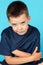 Close up portrait of little beautiful boy glancing right to the camera with stubborn look and mocking grin. Blue eyes, strong emot