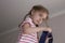 Close-up portrait of little girl is standing on the top of a ladder. the child is afraid