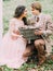 The close-up portrait of the lovely just married squating, looking at each other and holding the woven bos with the