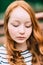 Close-up portrait of lovely thoughtful girl with long curly red hair in summer park. Outdoor portrait of a red-haired teenage girl