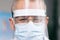 Close up Portrait of male Doctor in Glasses Wearing a Transparent Protective Face Shield, Mask and Overalls in a