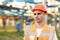 Close up portrait of male engineer in uniform and helmet standing outdoors. Man worker standing near big power electric