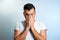 Close-up portrait of a man, covering his face with his hands. On a light background. The concept of body language