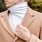 Close up portrait of man dressed in many layers of clothing - beige wool coat, cardigan and white high neck turtleneck - thermal