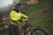 Close up portrait of a man on a mountain bike standing on a rocky terrain and looking at a rock. The concept of a