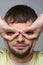 Close-up portrait of a man who made with his hands a kind of glasses on the eyes of European appearance