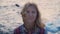 Close-up portrait of mature blonde woman who loves adventure travel on the background of the sea waves and wind