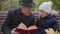 Close-up portrait of a mature Caucasian man in classic clothes sitting on the bench with his granddaughter and reading a