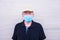 Close up and portrait of mature man and senior wearing medical and surgical mask - old man looking at the camera seriously -