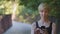 Close-up portrait middle-aged caucasian female lady blonde woman with short hair standing outdoors in park looking at