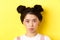 Close up portrait of moody asian girl pouting and looking upset at camera, standing wiht glamour makeup and hairbuns on