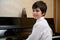 Close-up portrait of a multi ethnic teen boy, little pianist musician smiling looking at camera, sitting at piano forte