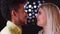 Close-up portrait of multinational couple watching tenderly into eyes on blurred lights background.