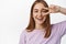 Close up portrait of natural young woman, candid smile of girl showing peace v-sign near eye, concept of woman beauty