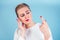 Close-up portrait of nervous unhappy young blonde woman looking at a broken fingernail and crying . red long nails