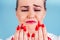 Close-up portrait of nervous unhappy young blonde woman looking at a broken fingernail and crying . red long nails