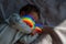 Close-up portrait of a newborn boy with a prism beam on his face. Rainbow.