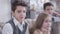 Close-up portrait of nice Caucasian brunette boy posing indoors as his twin brother and cute little sister sitting at