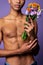 Close-up portrait of nude torso of boy with flowers in hand. Sensual latino young man posing