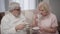 Close-up portrait of old Caucasian man and woman drinking tea at home. Happy mature spouses spending evening together