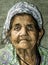 Close up portrait of old homeless Gypsy beggar woman with wrinkled face skin begging for money on the street in the city and looki