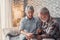 Close up and portrait of old woman checking pressure of his husband at home sitting not he sofa. Mature man feeling bad and sick