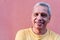 Close up portrait older Hispanic man leaning against wall and staring