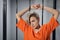 A close-up portrait of an orange-robed prisoner in prison against the background of prison bars