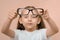 Close-up portrait of an out-of-focus preschool girl holding diopter glasses in front of her in focus